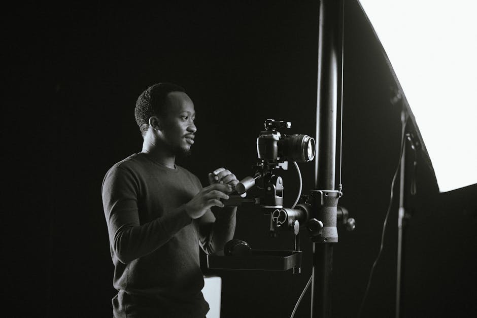 Black and white photo of a photographer in a studio adjusting equipment.